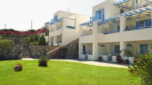 un grande edificio bianco con un cortile verde di Paros Paradise Apartments a Paroikia