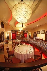 une salle à manger avec des tables et des chaises et un grand lustre dans l'établissement Taj Hari Mahal Jodhpur, à Jodhpur