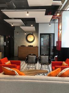 a lobby with red chairs and a clock on the wall at Be Lisbon Hostel Intendente in Lisbon