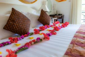ein Bett mit Blumen auf einem Zimmer in der Unterkunft Diani Sea Resort - All Inclusive in Diani Beach