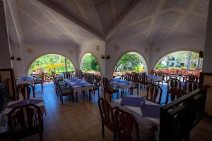 un comedor con mesas, sillas y ventanas en Diani Sea Resort - All Inclusive, en Diani Beach