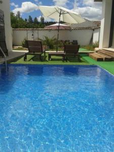 una gran piscina azul con 2 bancos y una sombrilla en Casa Oretani, en Picón