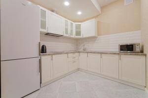 a kitchen with white cabinets and a microwave at Apartments on Krasnaya Street in Minsk