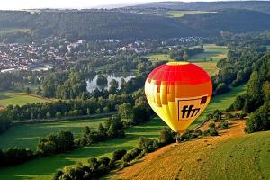 einem Heißluftballon, der über einem grünen Feld fliegt in der Unterkunft Ferienwohnungen Haus Fernblick in Bad König