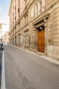 una calle vacía junto a un edificio con una puerta de madera en Appartamento del Nettuno en Bolonia