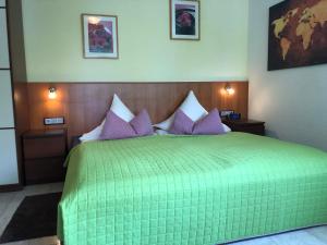 a bedroom with a green bed with purple pillows at Hotel Mühleinsel in Kenzingen +53 photos