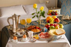 uma mesa de pequeno-almoço com alimentos de pequeno-almoço e bebidas numa cama em Residenza Canova Tadolini - Guesthouse em Roma