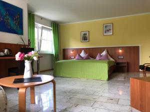 ein Schlafzimmer mit einem grünen Bett und einer Vase aus Blumen in der Unterkunft Hotel Mühleinsel in Kenzingen