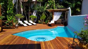 a pool on a wooden deck with chairs and a patio at Pousada Burundanga in Itacaré