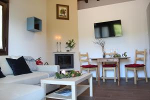 a living room with a white couch and a tv at Las Carriles Apartamentos rurales in Oviñana