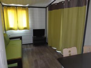 a living room with yellow curtains and a television at Résidence Lagrange Vacances - Les Cottages Varois in Solliès-Toucas