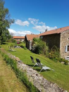two chairs sitting in the grass next to a house at Se reconnecter à la nature au gîte 3 étoiles de Montager à Saint André de Chalencon in Saint-André-de-Chalençon