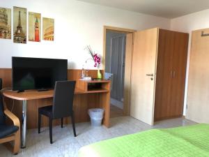1 dormitorio con escritorio, TV y cama en Hotel Mühleinsel, en Kenzingen