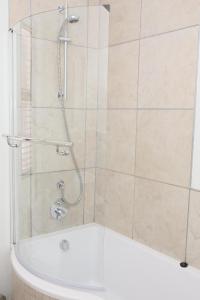 a shower with a glass door and a tub at CAG The Cube Rivonia in Johannesburg