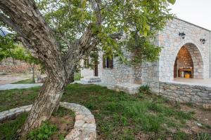 a tree in front of a stone building at ARADENA TRADITIONAL House 4 in Arádhaina