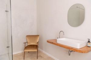 a bathroom with a sink and a chair at Chartfield Guesthouse in Kalk Bay