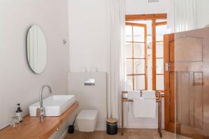 bagno con lavandino, servizi igienici e specchio di Chartfield Guesthouse a Kalk Bay