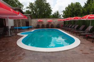 a swimming pool with chairs and umbrellas at Kladenetsa Guest House in Ivanovo