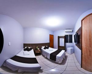 um quarto de hotel com duas camas e uma televisão em Pousada das Maracanãs em Maracanaú