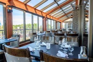 a dining room with tables and chairs and windows at Hotel Le Montagnais in Saguenay