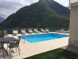 a swimming pool with chairs and a table and a mountain at Villa Lilla in Argegno