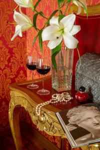a table with two glasses of wine and a vase of flowers at Residenza Canova Tadolini - Guesthouse in Rome