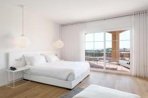 a white bedroom with a bed and a balcony at Ama Islantilla Resort in Islantilla