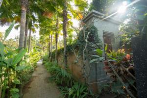 a path leading to a house with palm trees at Royani Villa in Sukawati