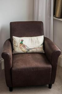 a brown chair with a pillow with a chicken on it at Beachlands Hotel in Weston-super-Mare