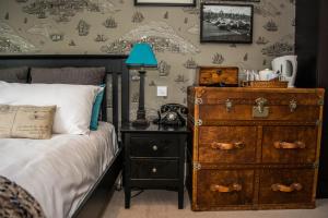 a bedroom with a bed and a dresser with a lamp at Beachlands Hotel in Weston-super-Mare