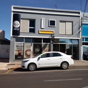 um carro branco estacionado em frente a um edifício em Hostel Senhor do Café em Botucatu