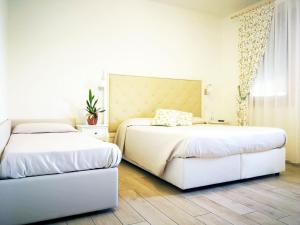 two beds in a bedroom with white walls and wooden floors at Agriturismo Casa Rossa in Postioma