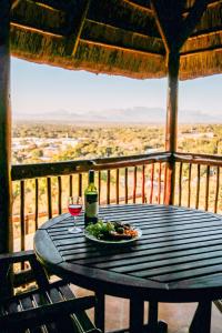 a table with a plate of food and a glass of wine at Maroela Guest Lodge in Thabazimbi