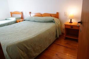 - une chambre avec un lit et une table de nuit avec une lampe dans l'établissement Apart Flavia, à Carhué