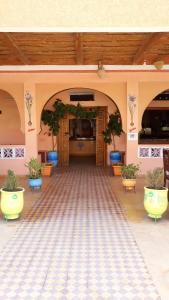 une entrée à un bâtiment avec des plantes en pot sur le sol dans l'établissement Auberge Restaurant le Safran Taliouine, à Taliouine