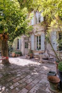 ein Haus mit einer Terrasse mit Stühlen und einem Baum in der Unterkunft Maison XIXe et Jardin en Intramuros in Avignon