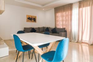 a living room with a white table and blue chairs at Marina Rabat Suites & Apartments in Salé