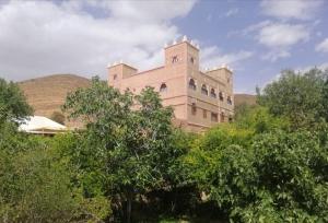 een gebouw met een toren bovenop enkele bomen bij Auberge Restaurant le Safran Taliouine in Taliouine