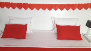 a white bed with two red pillows on it at Barrocas do Mar in Prainha de Baixo
