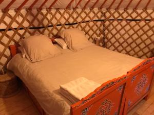 een bed in een yurt met witte lakens en kussens bij yourte Coeur de Combray in Ernes