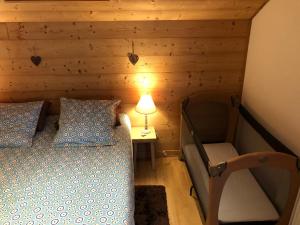 a bedroom with a bed and a lamp and a chair at AU COEUR DES ALPES in Marignier