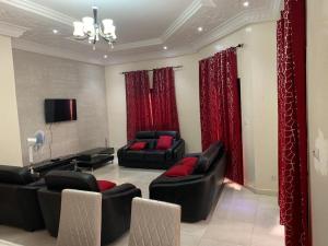 a living room with two couches and red curtains at Belle Villa Nassima in Thiès