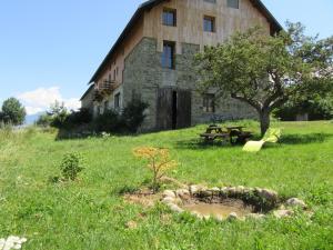a building with a table and a tree in a field at Gîte Potimarron in Ancelle