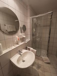 a white bathroom with a sink and a shower at Hotel Römerhof in Straubing