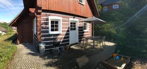 a log cabin with a table and a grill at Modern chalet Na Zlatníku in Zlatá Olešnice