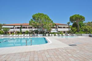 a swimming pool with chairs and a building at SABBIADORO in Cavallino-Treporti