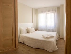 1 dormitorio con 1 cama blanca y 2 toallas en Apartamento Rosaleda, en Melide