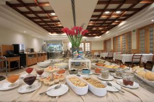 ein langer Tisch mit vielen Schüsseln und Tellern voller Essen in der Unterkunft Consolata Hotel in Fátima