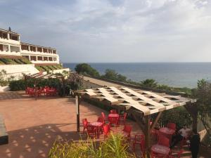 un patio con mesas y sillas rojas y el océano en Costa Makauda Residence, en Sciacca