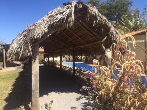 a thatched umbrella next to a swimming pool at Hospedagem Portal da Terra in São João